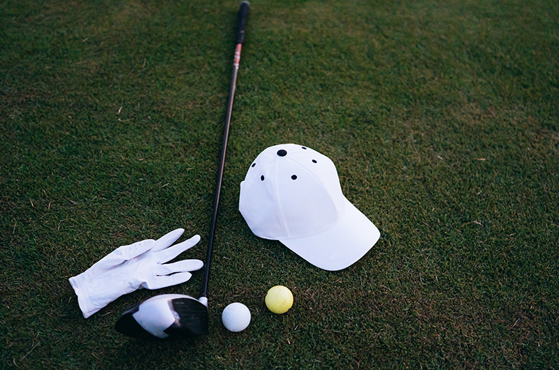 hat, club, gloves, and golf balls on green